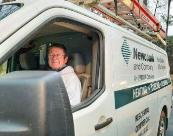 Newcomb team member posing while sitting in the front seat of work van